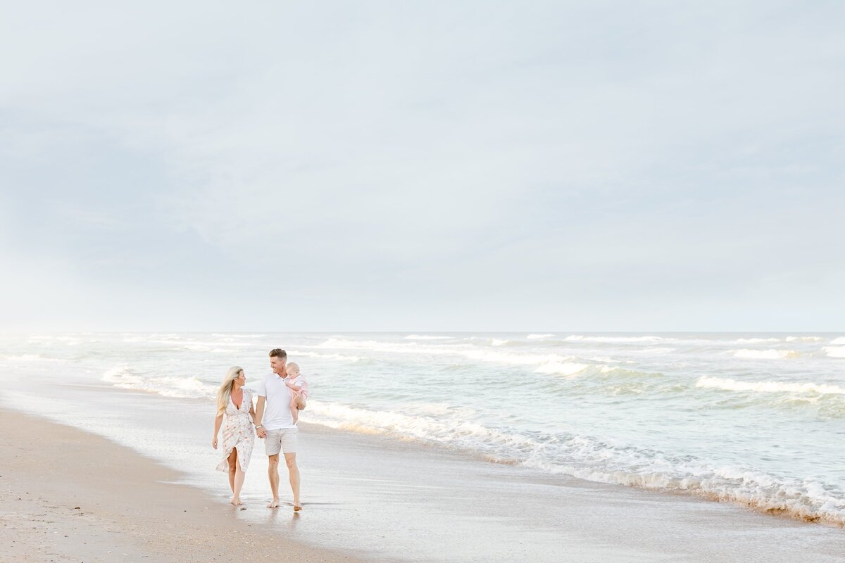 Parents and baby boy walking down the beach