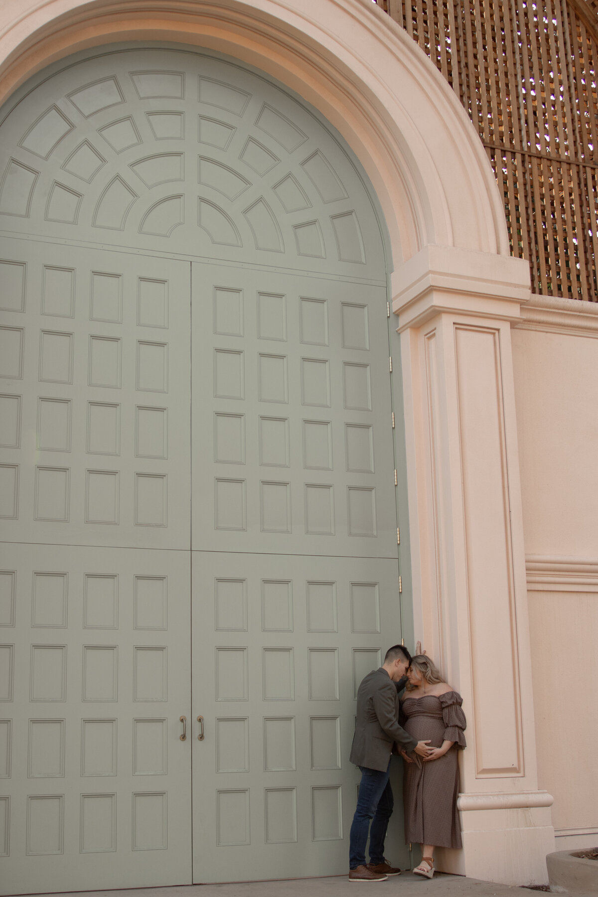expecting mom and dad having an intimate moment in front of the botanical building in balboa park