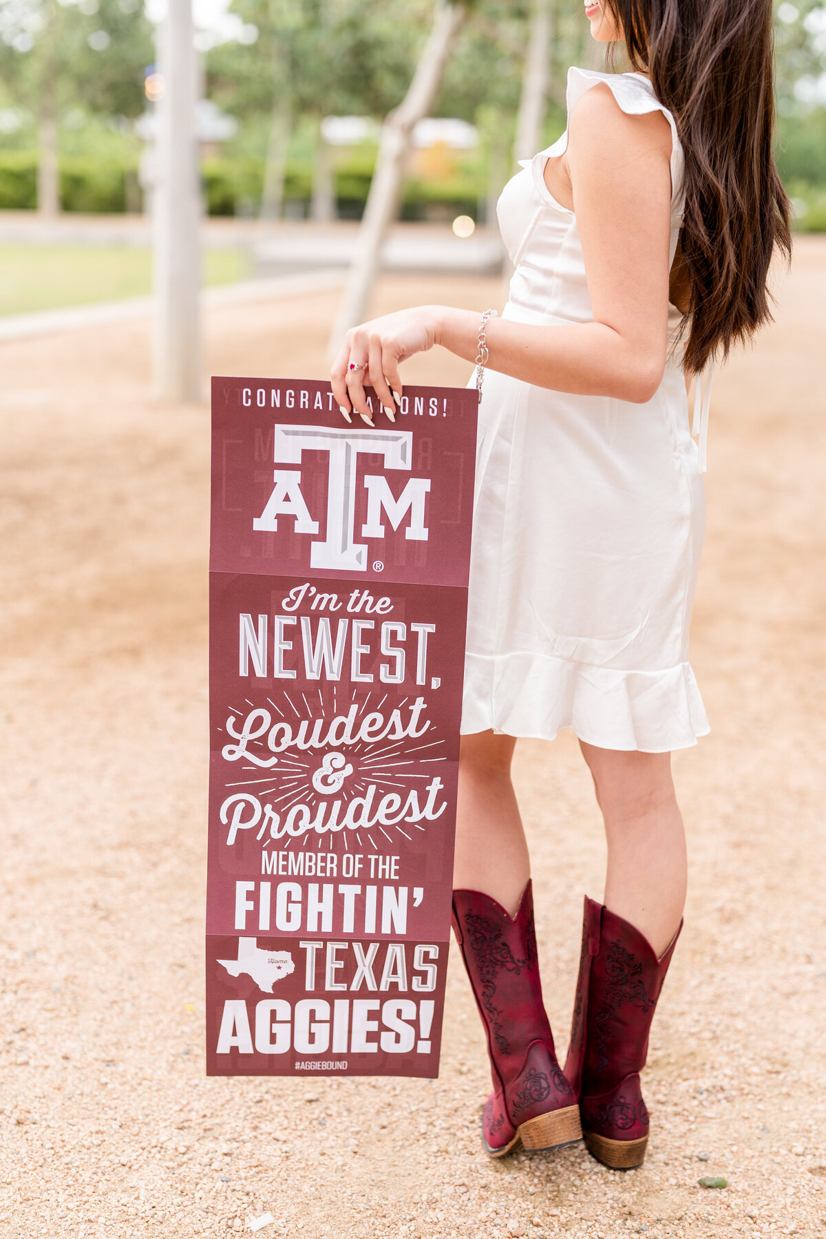 Houston high school senior girl holding Texas A&M acceptance letter at side with maroon cowboy boots in Downtown Houston