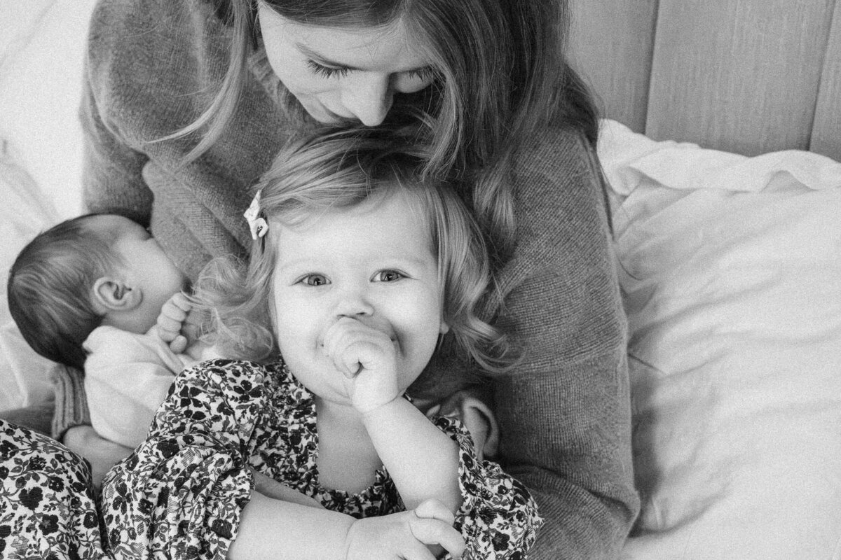 Toddler sucking her thumb while sitting on her mother’s lap, both looking calm and relaxed.