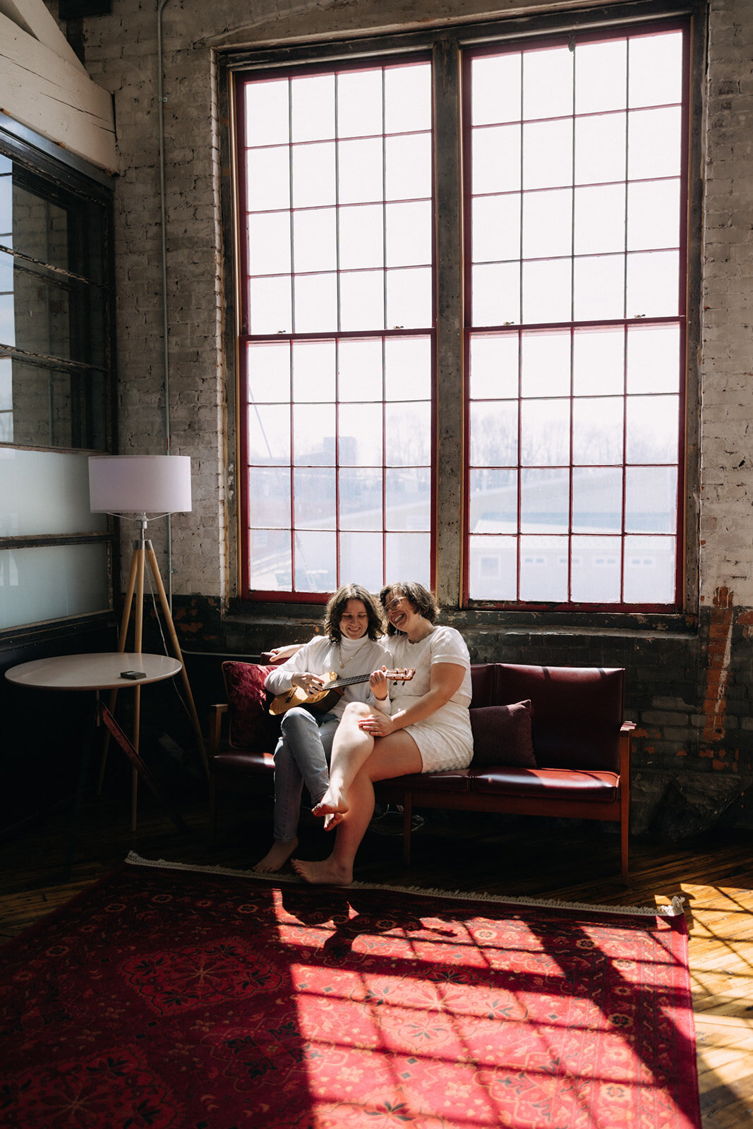 Queer Couple sitting on sofa reading a note at Finger Lakes wedding, NY