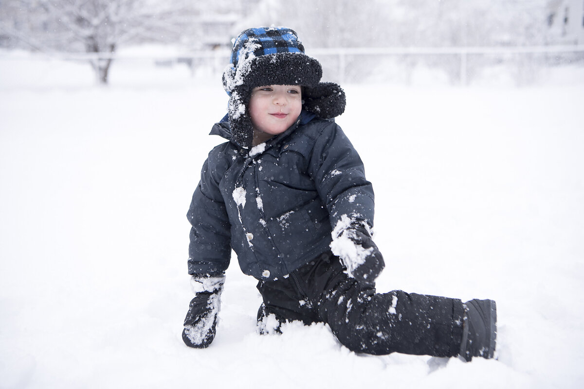 A small child in winter clothes playing in the snow 