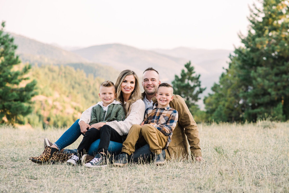 family outdoor photos with parents sitting in a field with their little children with the Rocky Mountains in the distance for fall family pictures