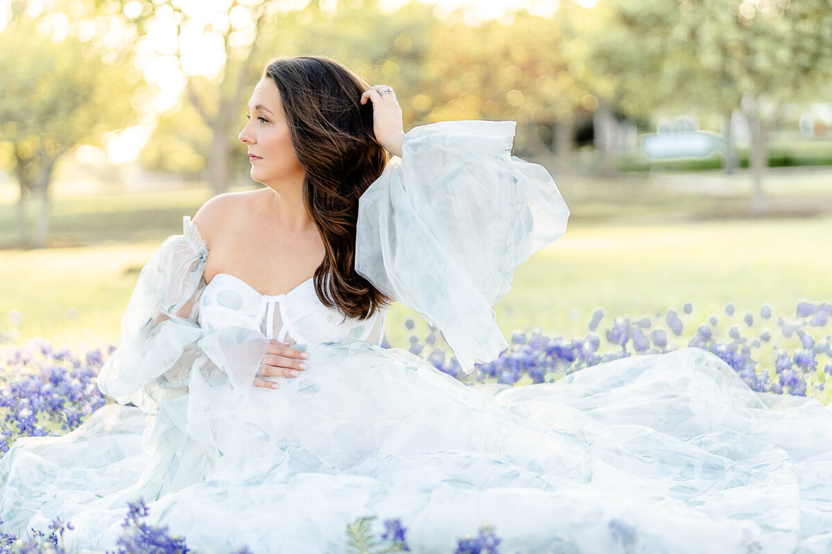 momma to be in maternity fashion gown surrounded by bluebonnets