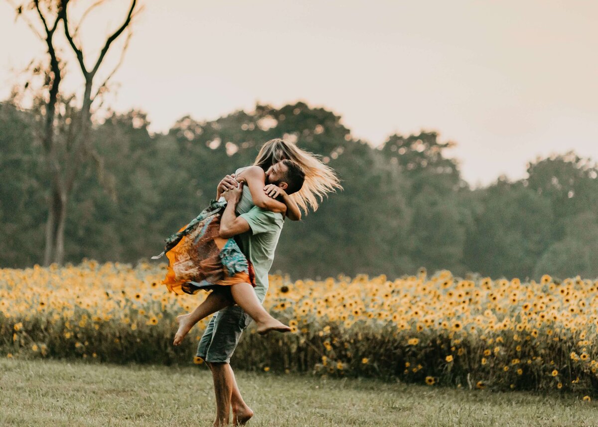 A man and woman embracing in a sunflower field captured by a Pittsburgh family photographer.