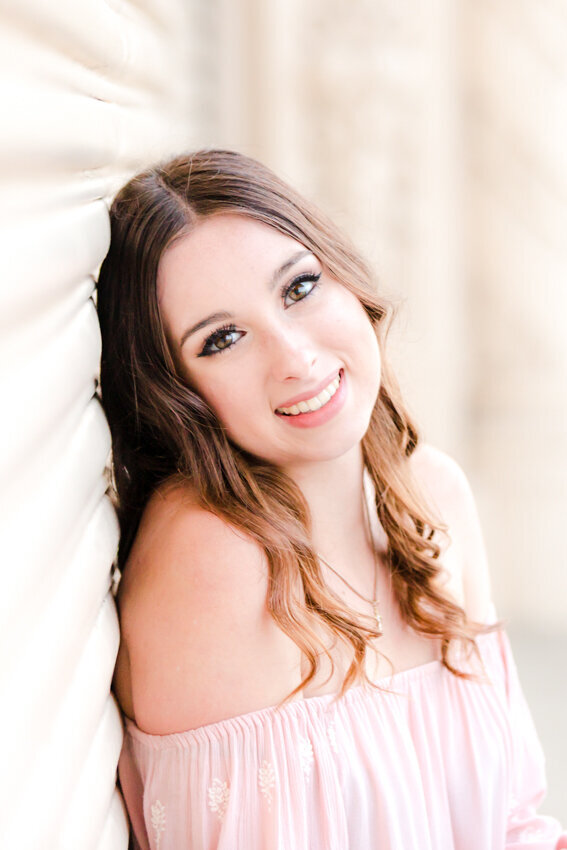 Senior girl leaning against white wall