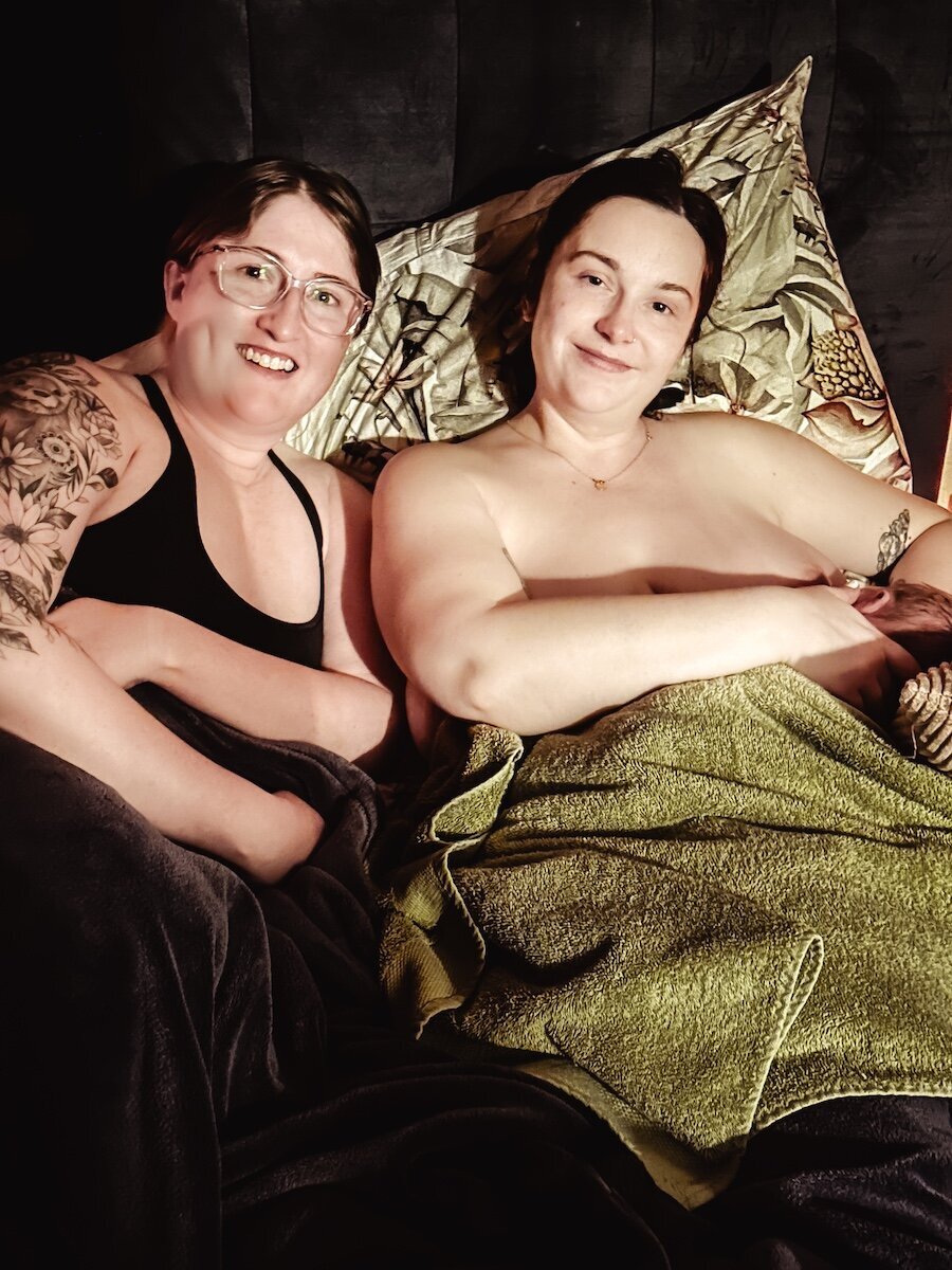 lesbian couple smile after the birth of their child