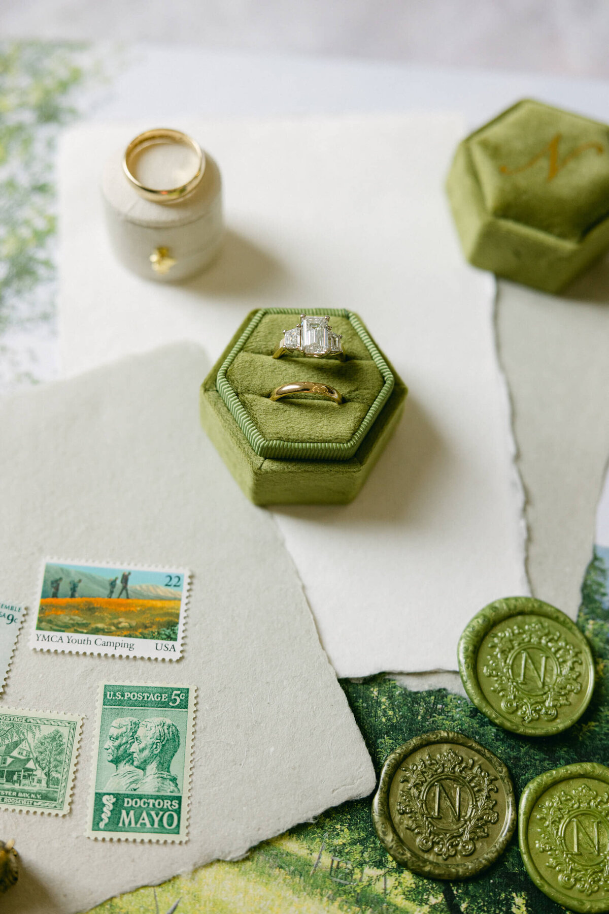 A wedding day detail photo of the couples rings , invitations and wax stamps