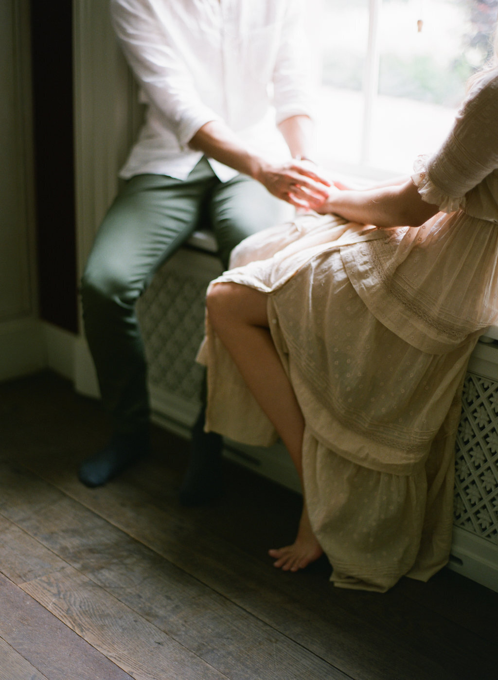 Couple holding hands sitting on window sill in Los Angeles