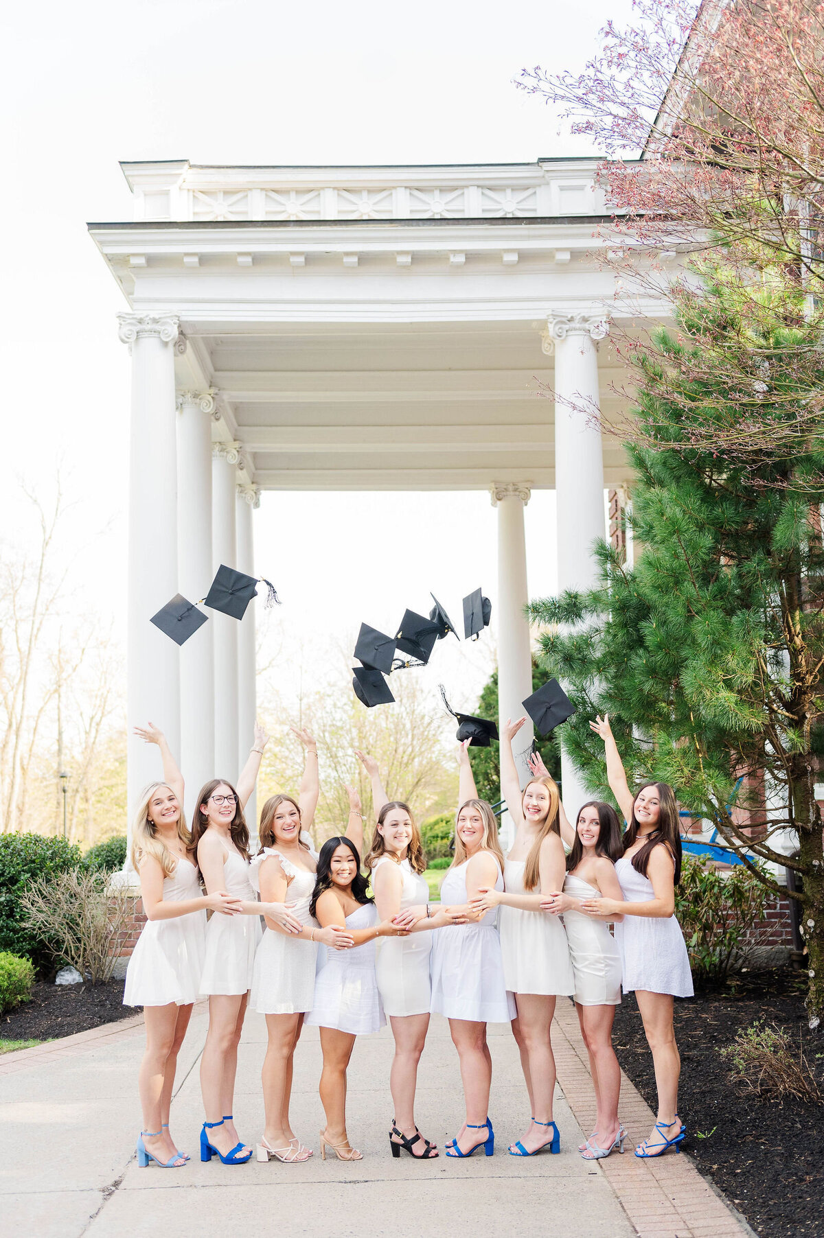 Group of girls throwing grad caps at Assumption University taken by best college grad photographer in Worcester, MA