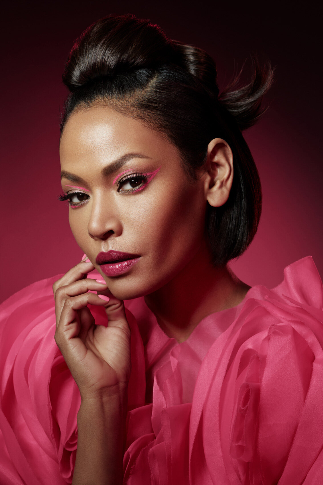 Amira in a vibrant pink look, showcasing bold makeup and a poised expression, captured by Ylva Erevall.