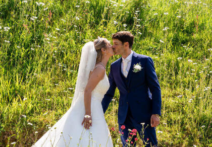 A bride and groom kissing in a field of wildflowers