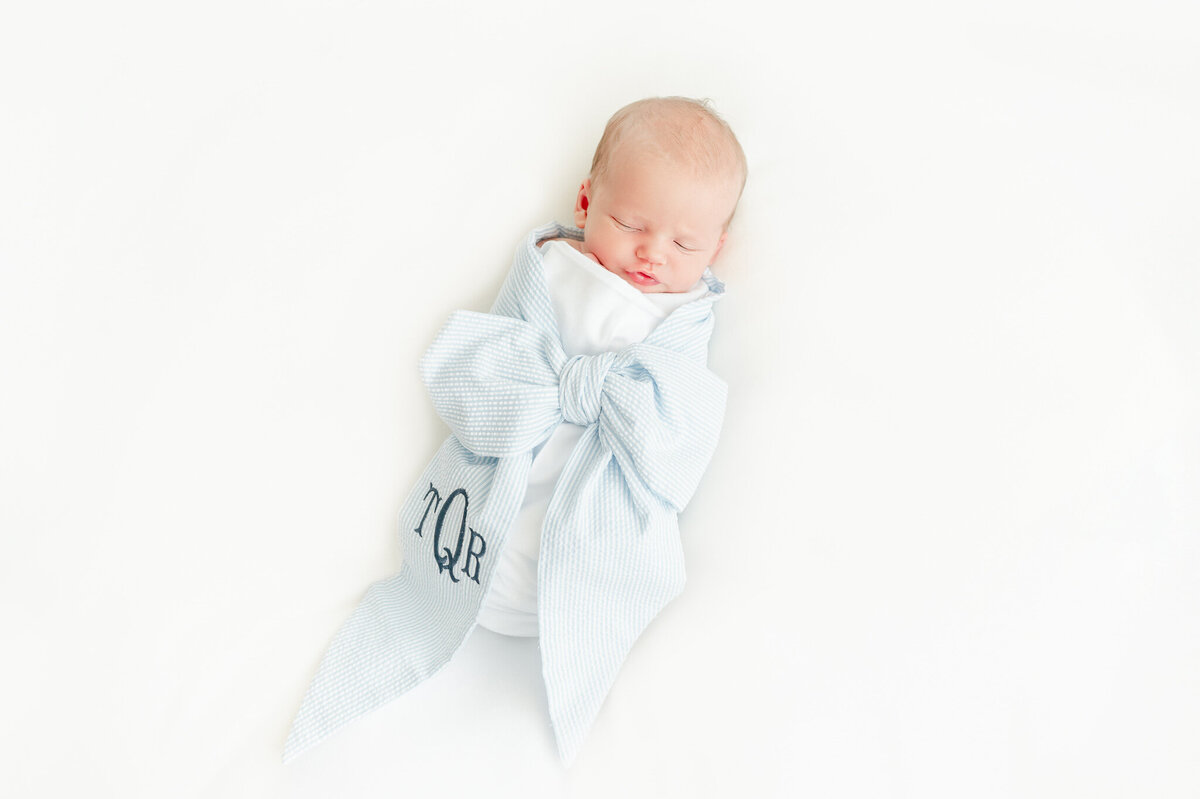 Baby boy wrapped in a beaufort bonnet bow swaddles sleeps In Kristie Lloyd’s Nashville newborn photographer studio