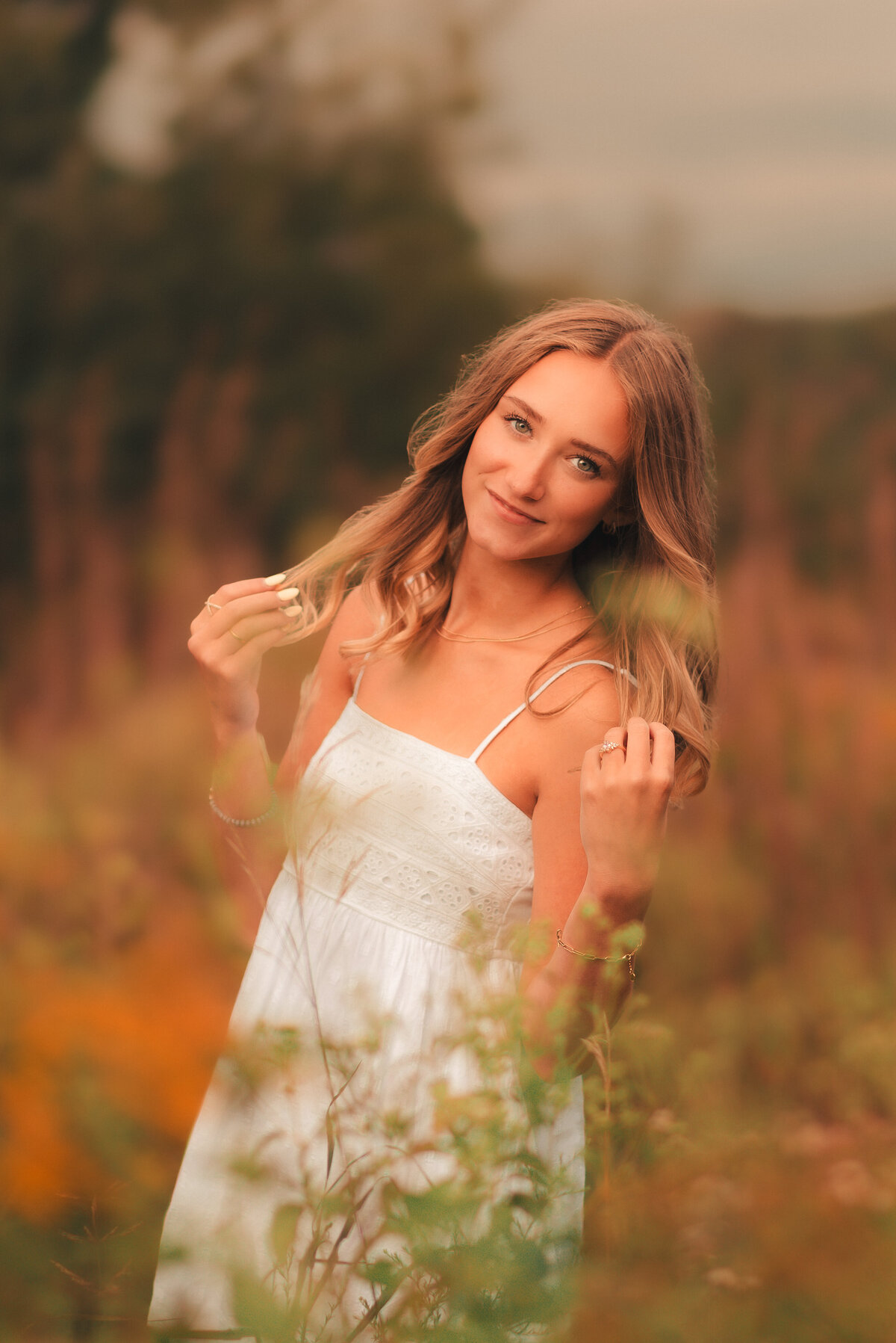 Senior girl photographed with backlit golden sunlight in outdoor meadow during senior portrait session in Minnesota.