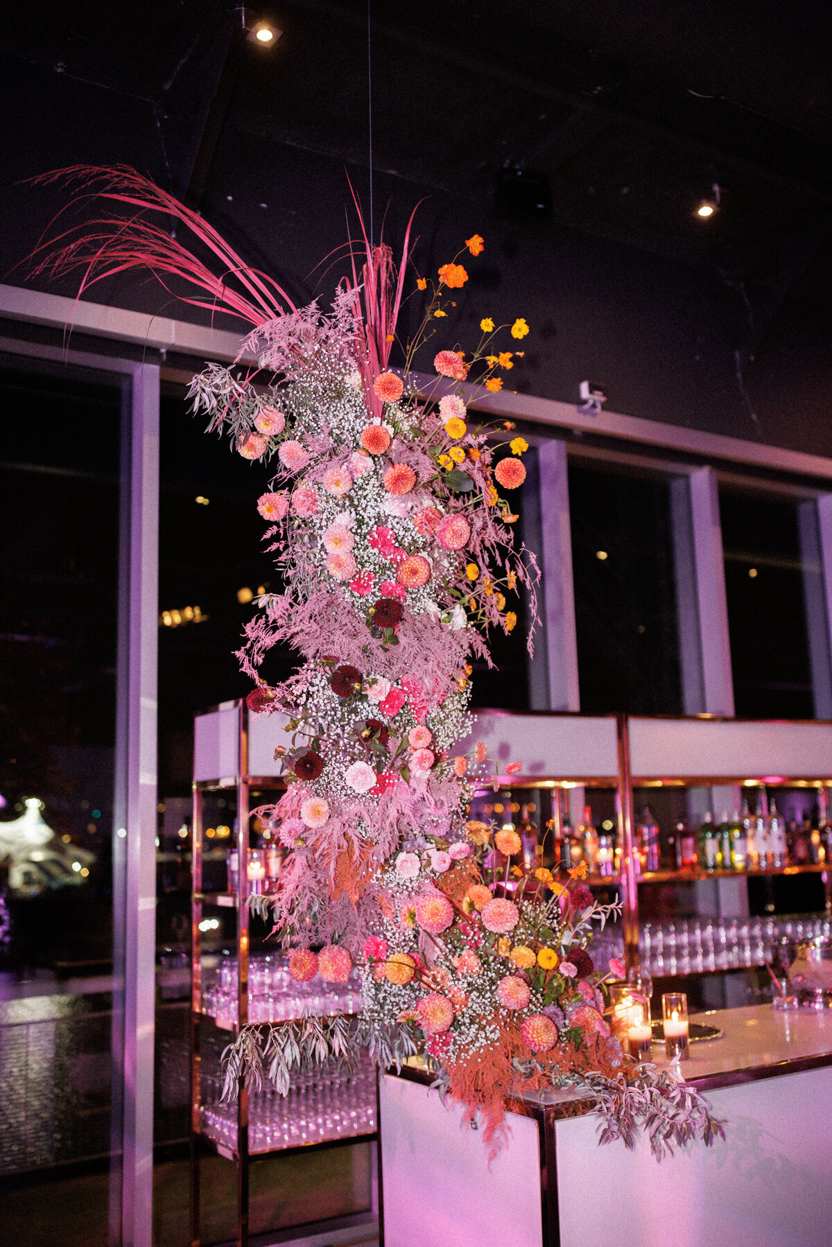 A colourful, modern flower arrangement bathed in pink light at a wedding bar at the Science Centre. 