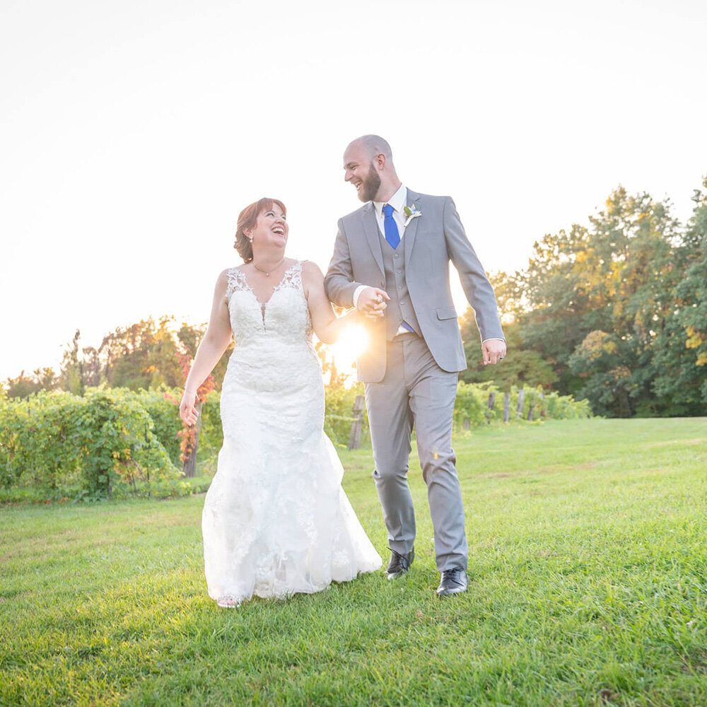 bride and groom walking together in front of setting sun