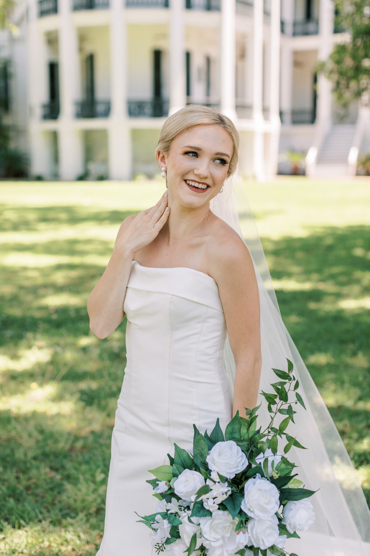 A bride laughs backward in front of Nottoway Plantation.