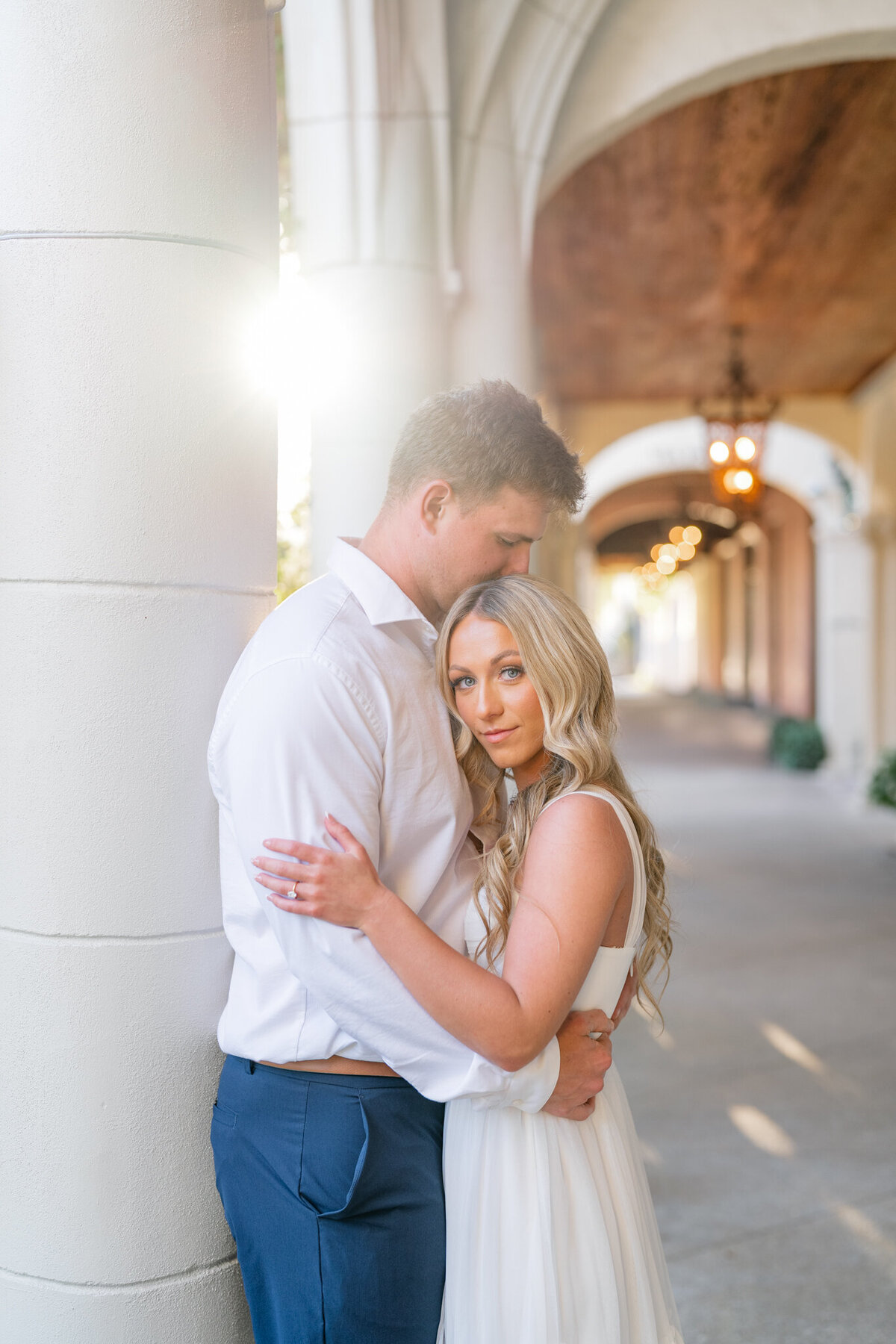 Couple snuggling with the sun peaking out from behind a column