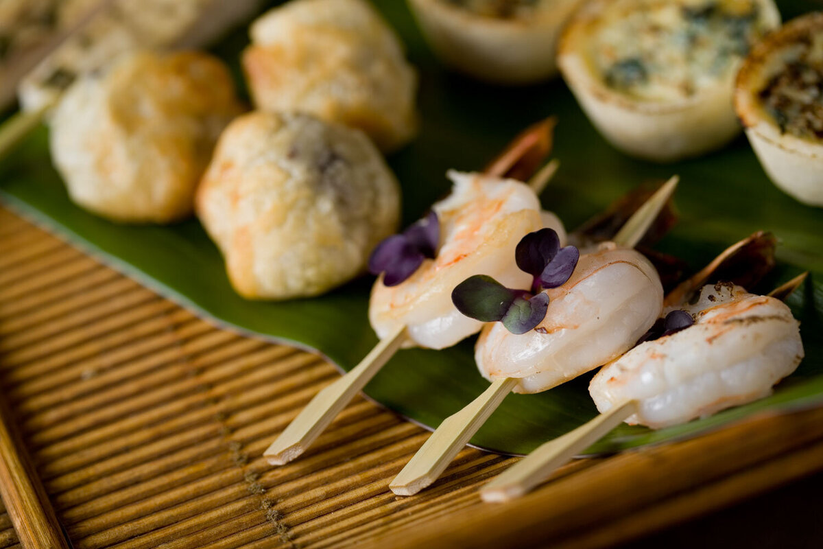 A close up of shrimp on skewers on a green leaf