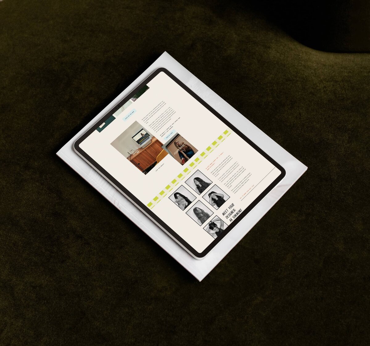 A tablet displaying a webpage is placed on top of a white folder, which is lying on a dark green surface. The webpage showcases an article about brand designer services and several images of people in a grid format.