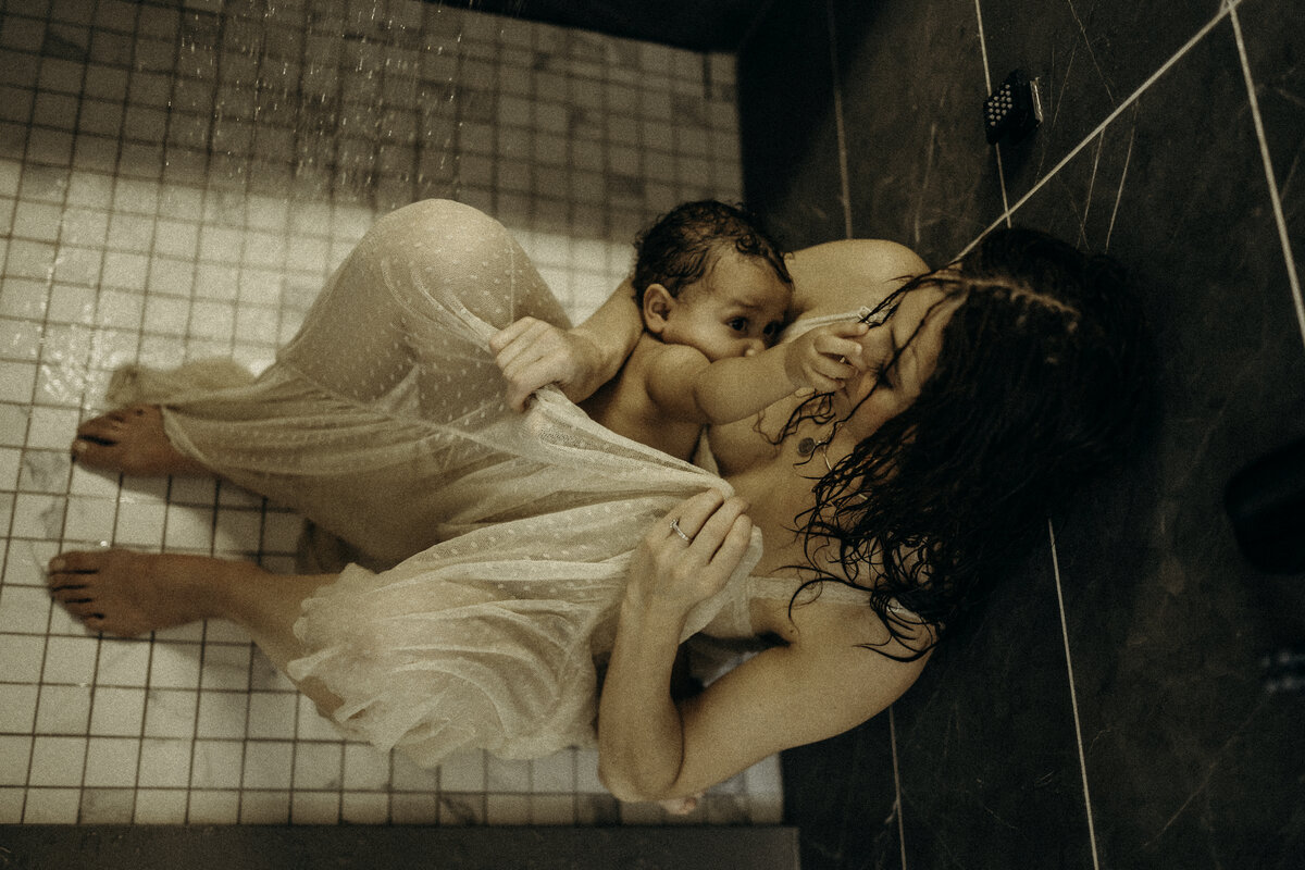 mother sitting in shower with baby boy