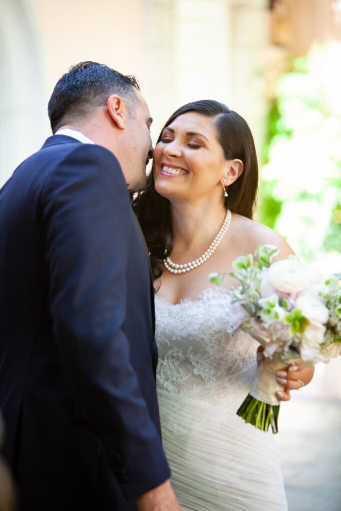 A groom leaning in to kiss a bride's cheek