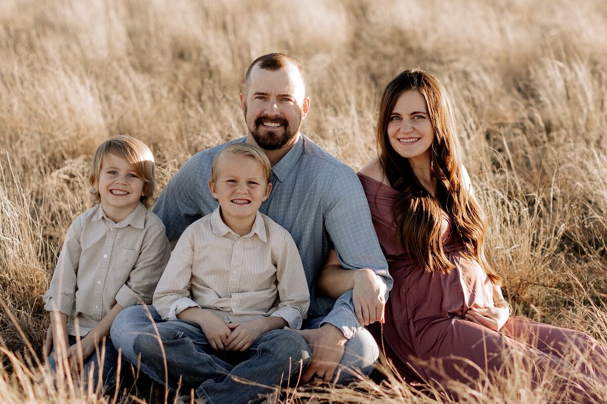 maternity photography of a family sitting in the grass