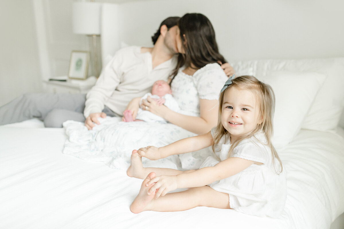 a family hanging out on the bed with their newborn