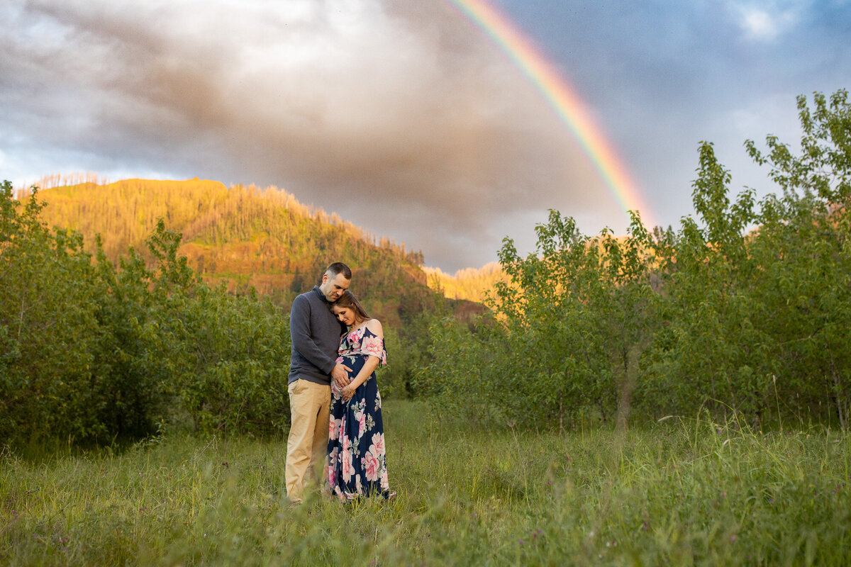 Couple stands under a rainbow in field near Portland, Oregon.