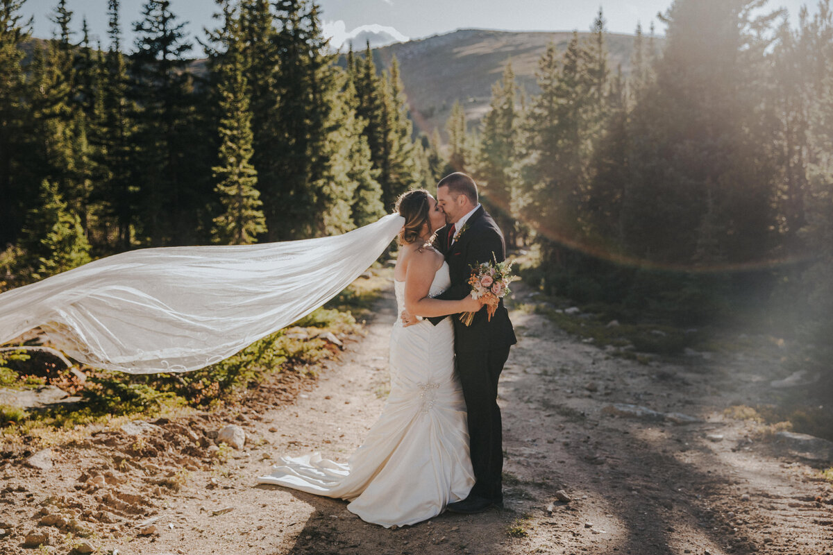 A bride and groom kiss in the Rocky mountains