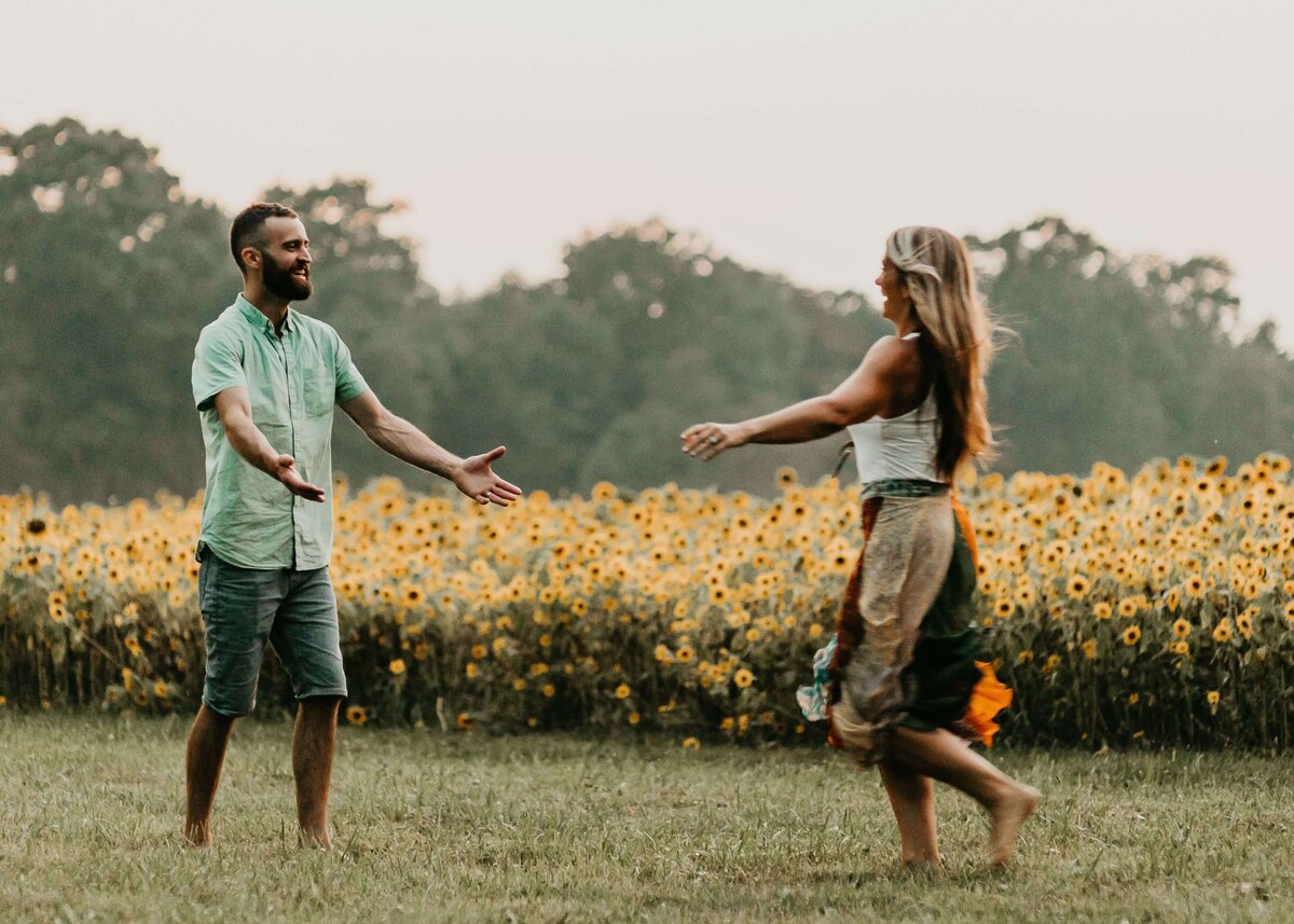 A man and woman dancing in a field of sunflowers captured by a Pittsburgh family photographer.