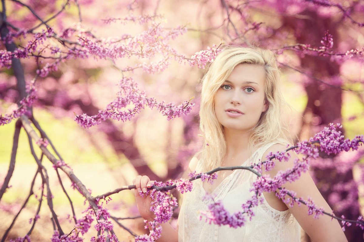 high school senior photo of girl in purple blossoms with white top