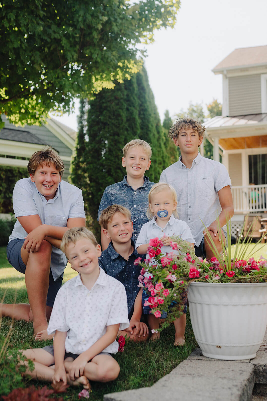 Young boys at a range of ages sitting by a tub of flowers