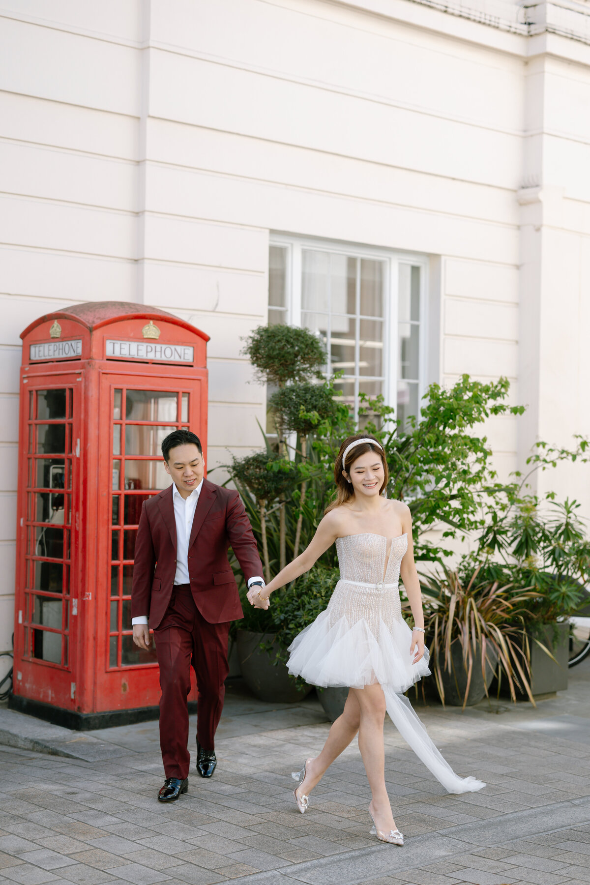 man and woman holding hands infront of red phone box in london