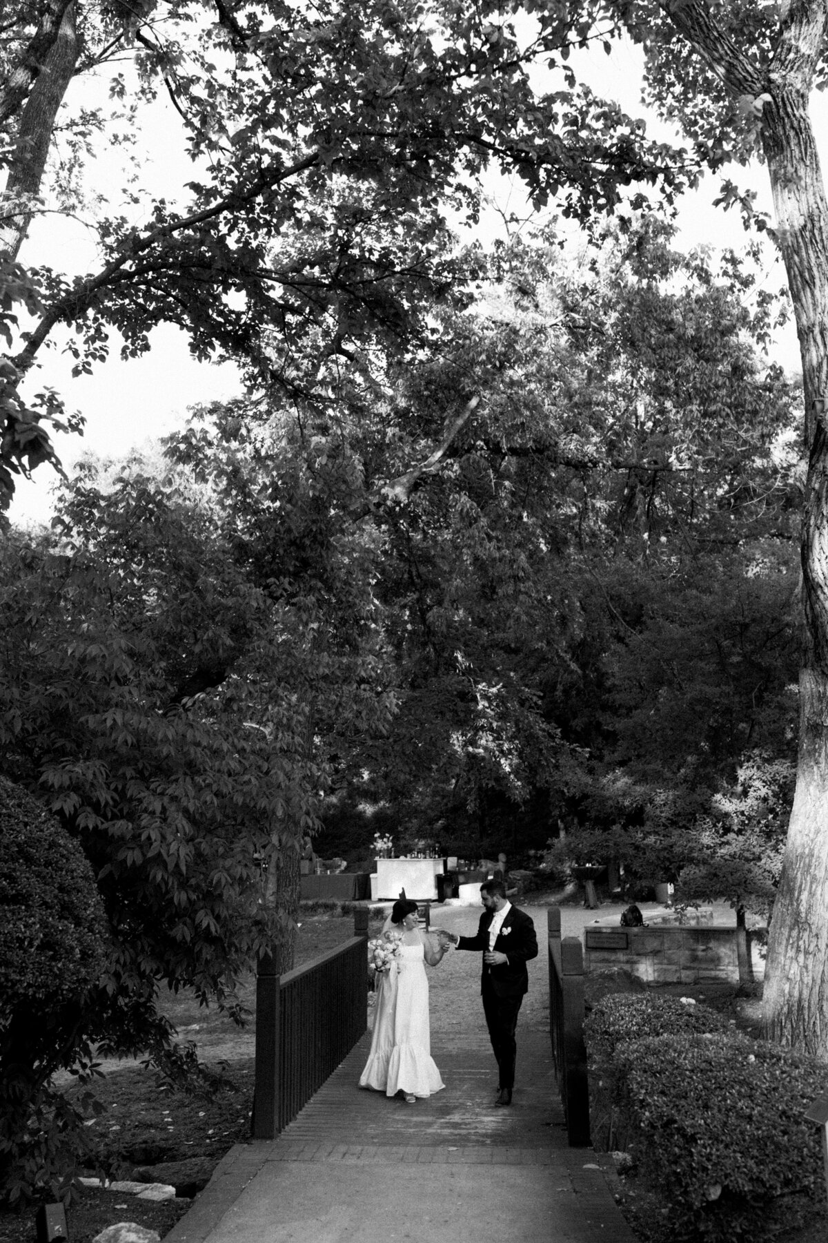 Bride and groom walking along path at Couple portraits in the grounds of Umlauf Sculpture Garden, Austin