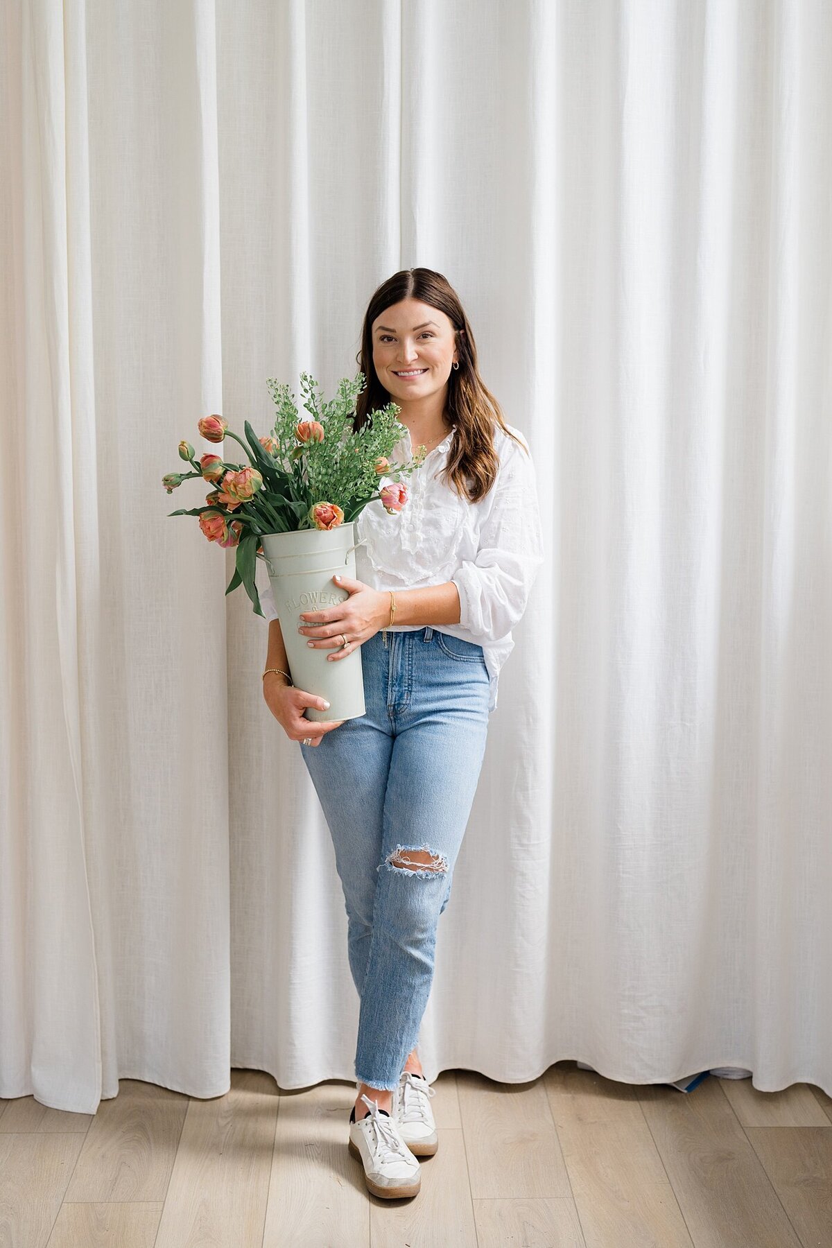 Columbus photographer photographs small business owner holding a tall container filled with long stem flowers for her branding photography