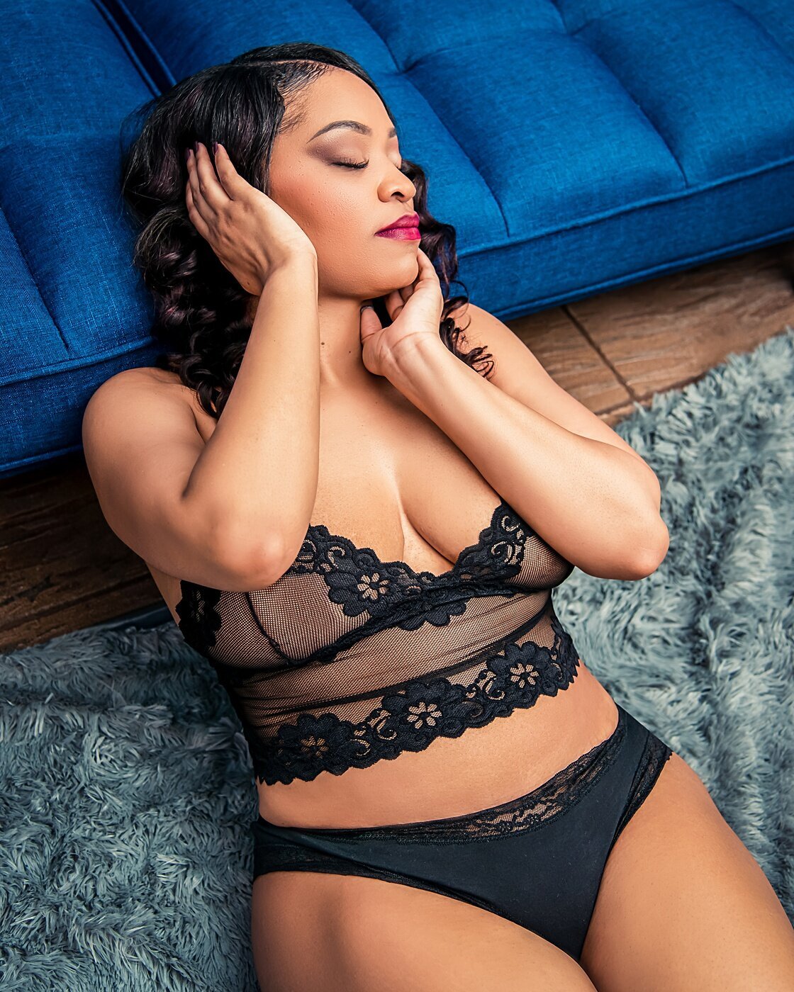A woman in black lace lingerie poses during her boudoir photoshoot.