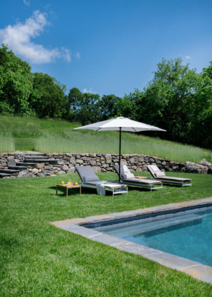 Boston interior designers design a modern outdoor space at a new pool, blending contemporary style with comfort for a seamless and inviting outdoor retreat.