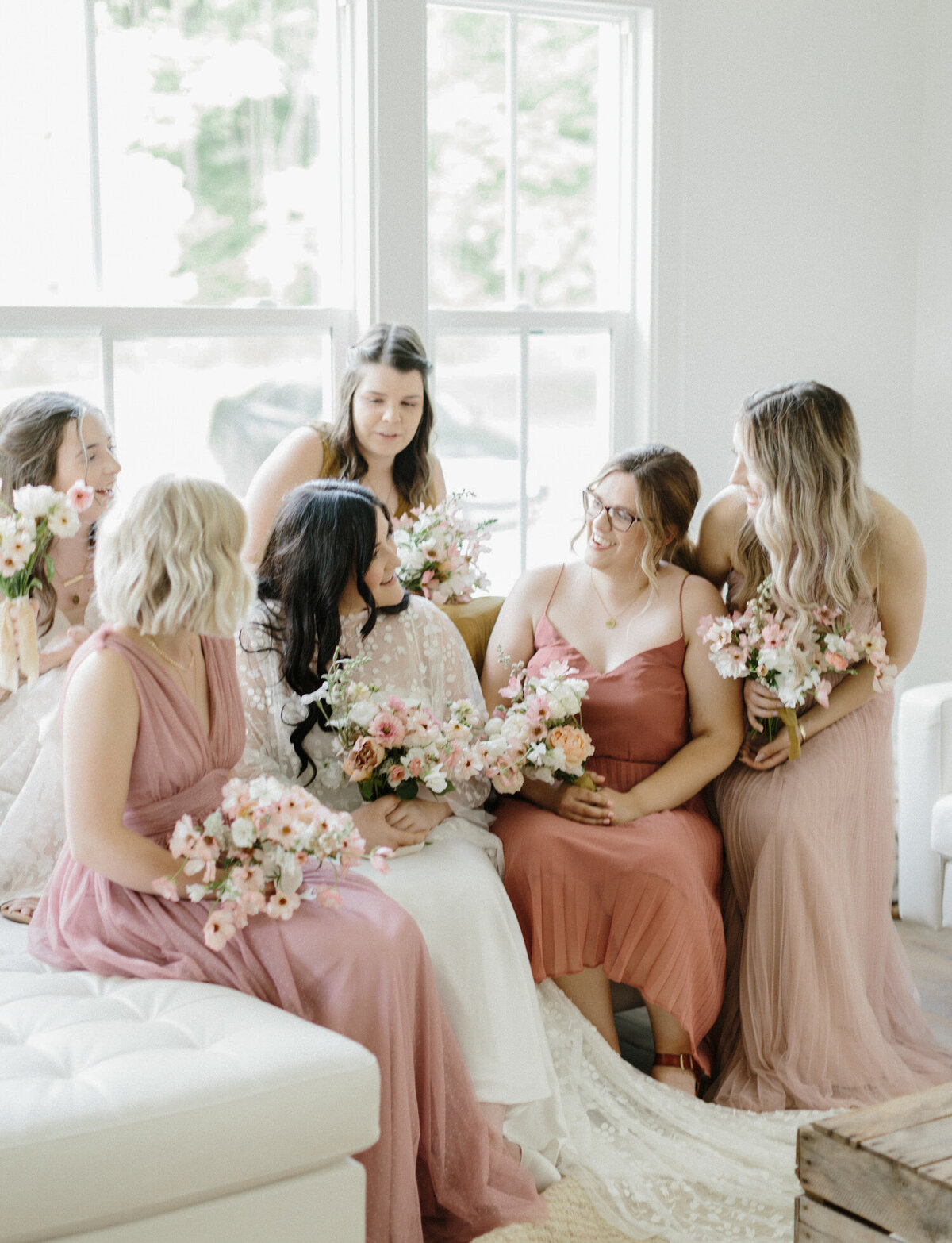 bridesmaids in warm pink colors laugh together at Glass House Community, Michigan wedding venue