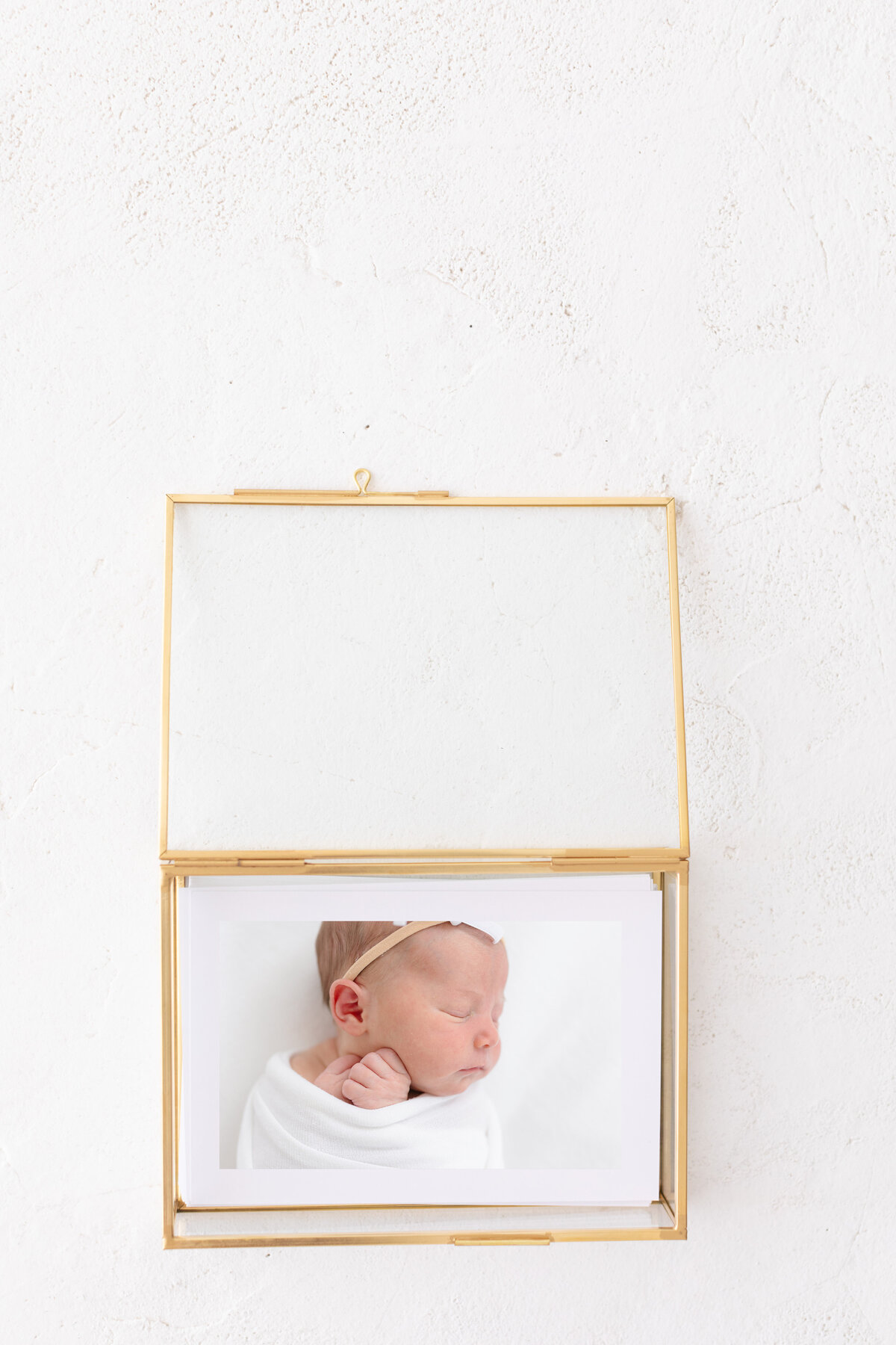 Glass box full of photos from a newborn session taken by Missy Marshall newborn photographer