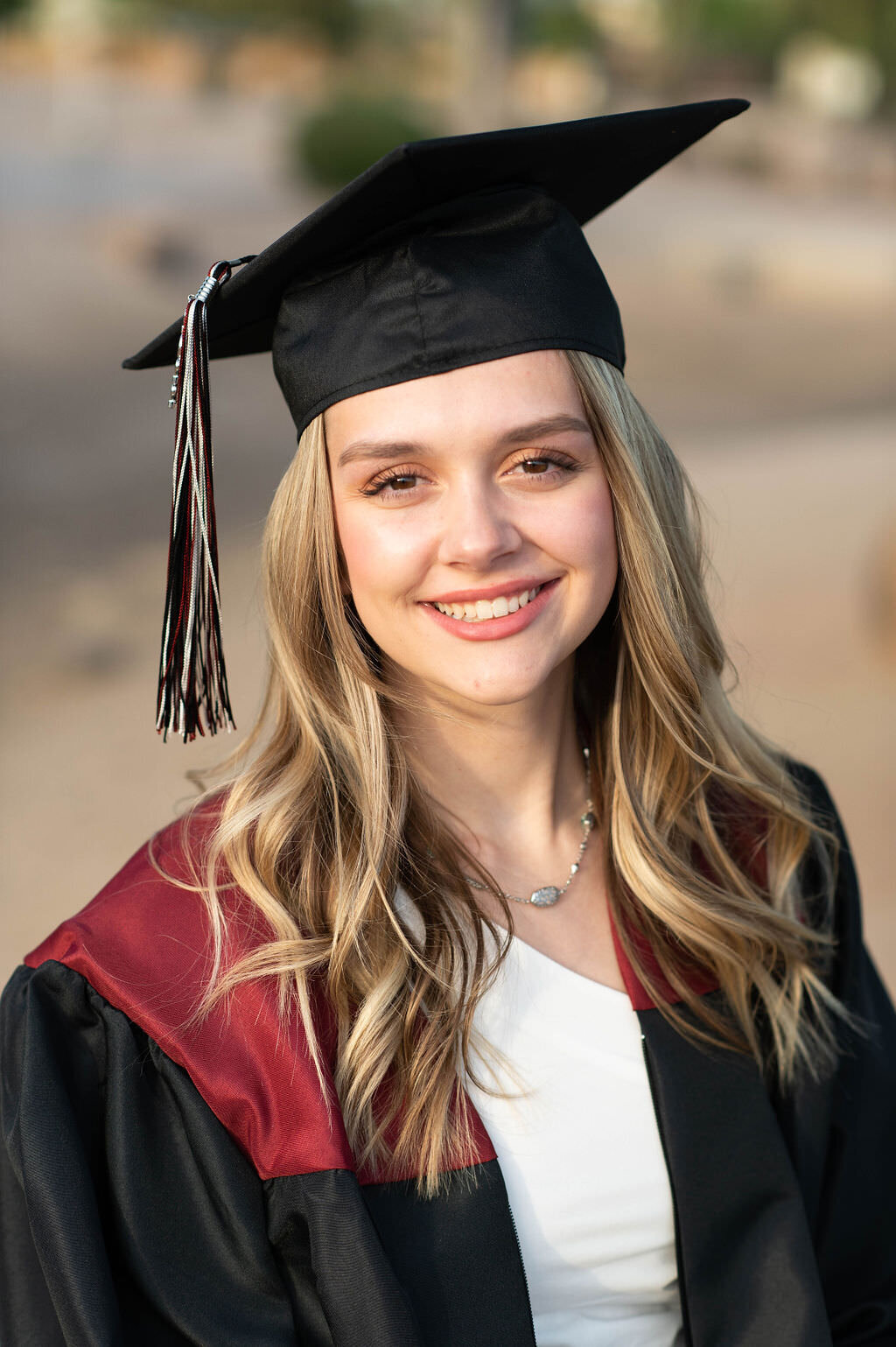 A girl in a graduation cap and gown smiling.
