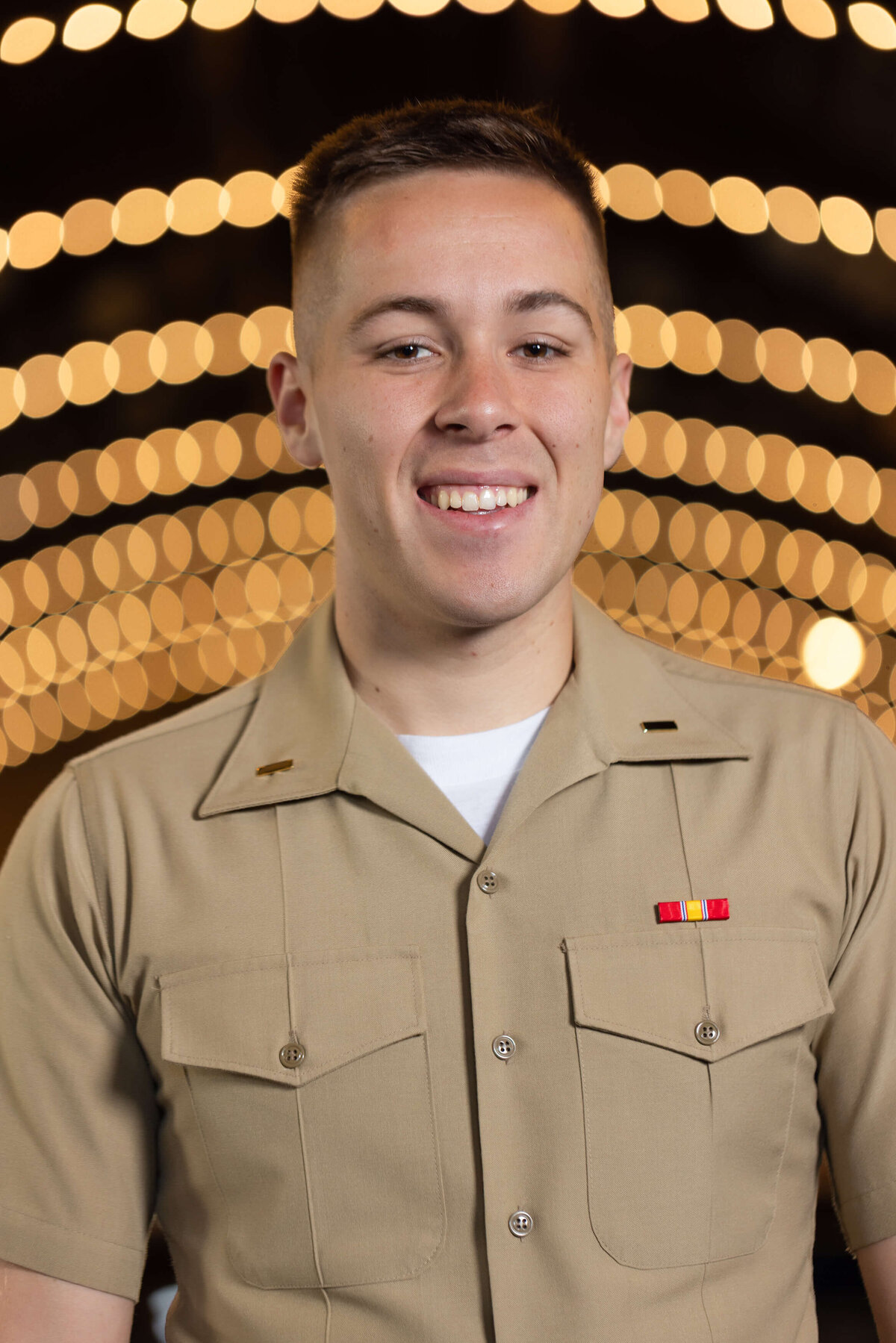 U.S. Marine Corps officer smiles with bokeh lights background.