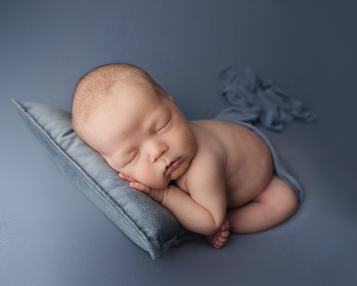 Baby boy sleeps with hand on chin pose for newborn photo in Murrysville studio.