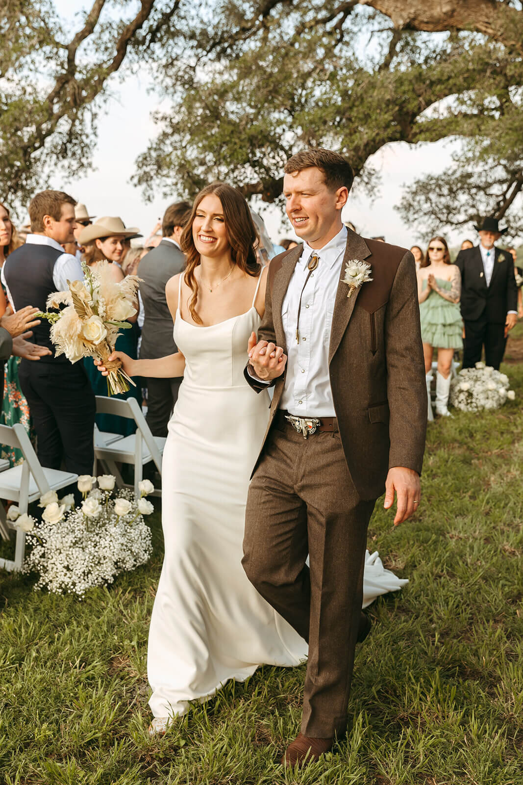 Bride and groom walk down the aisle at rustic Austin wedding with on-site professional bridal hair and makeup services by Mistique Makeup.
