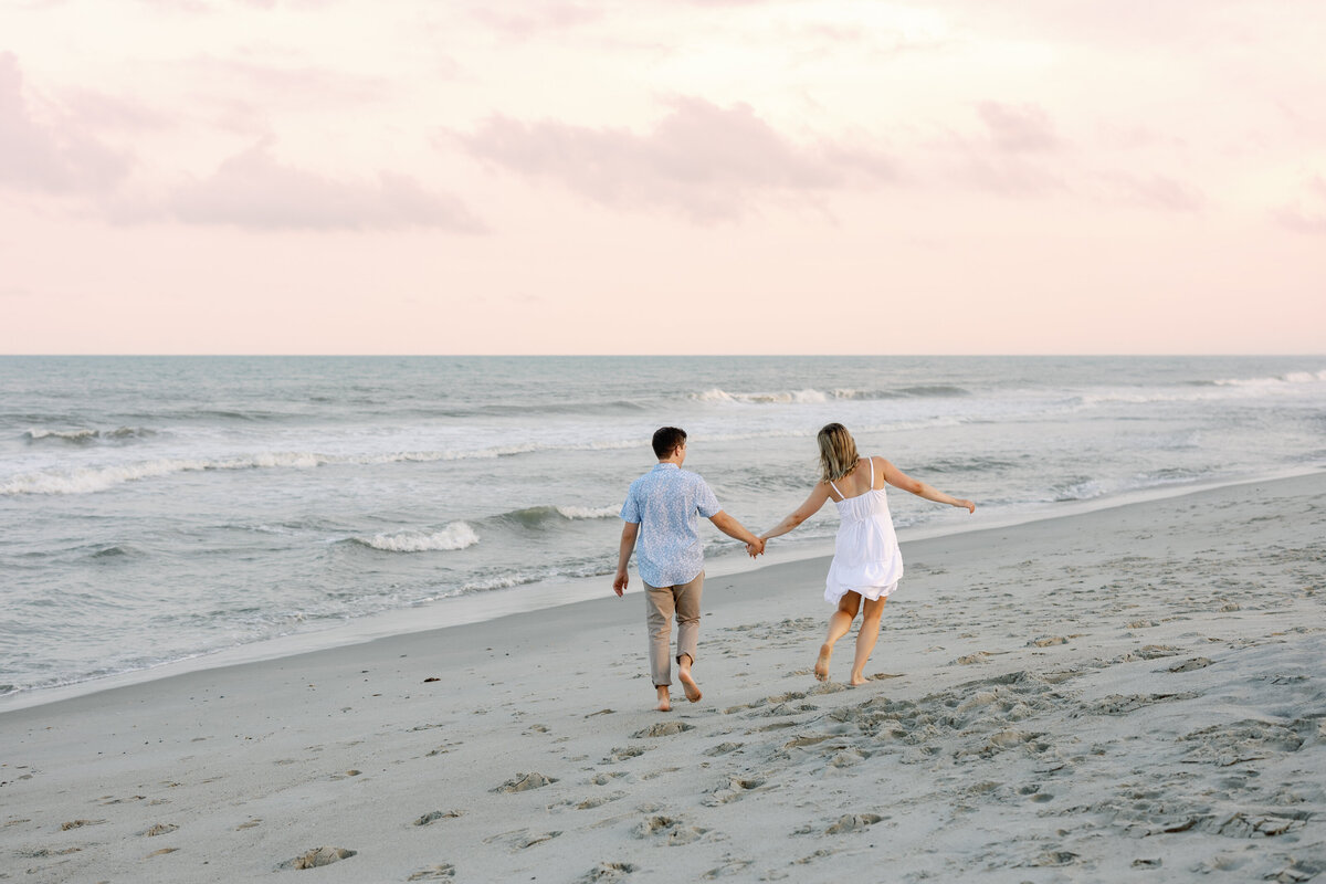 Couple running along Wilmington shoreline, action engagement photography