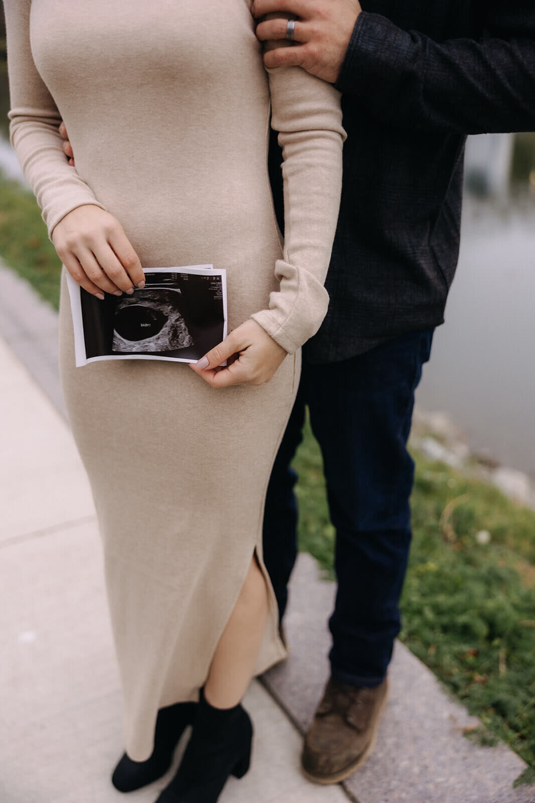 couple standing by lake holding scan photo for  maternity photos in Finger Lakes New York