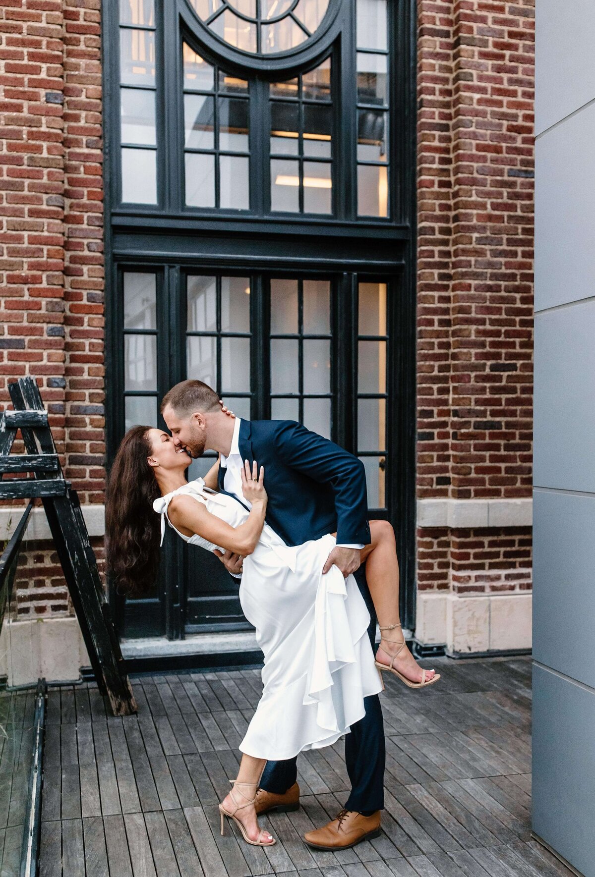 husband and wife dip kiss on city rooftop by baltimore wedding photographer sabrina leigh