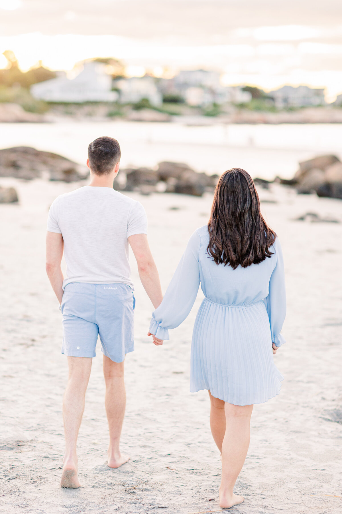 Couple holding hands walking away from the camera representing romantic MA beach engagement pictures