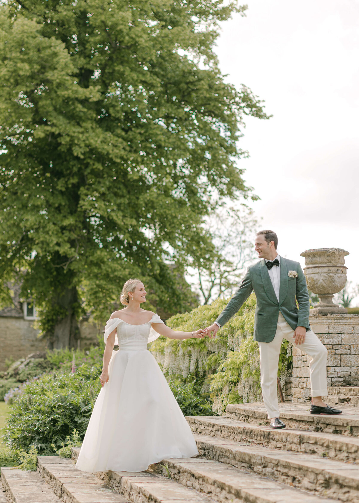 chloe-winstanley-weddings-cotswolds-cornwell-manor-monique-lhuillier-bride-holding-hands-steps