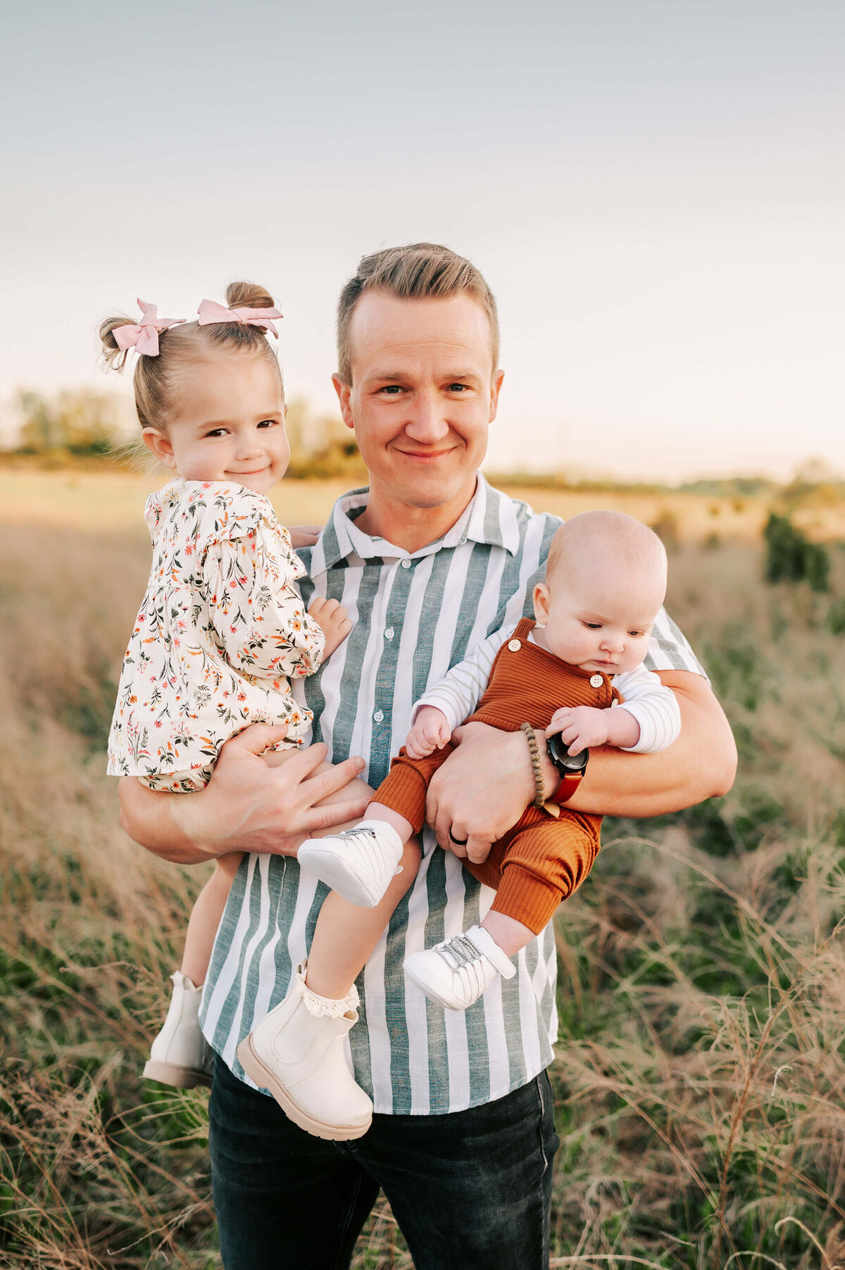 family pictures in Springfield MO of dad holding kids outdoors at sunset